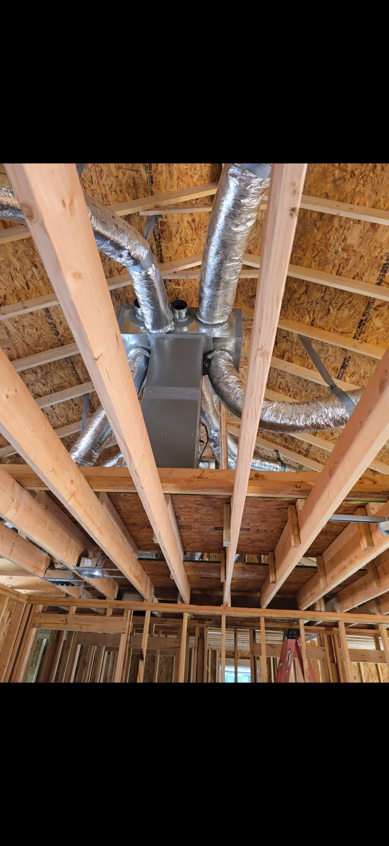 HVAC flex ducts with reflective insulation and electrical wiring in wooden framed ceiling cavity