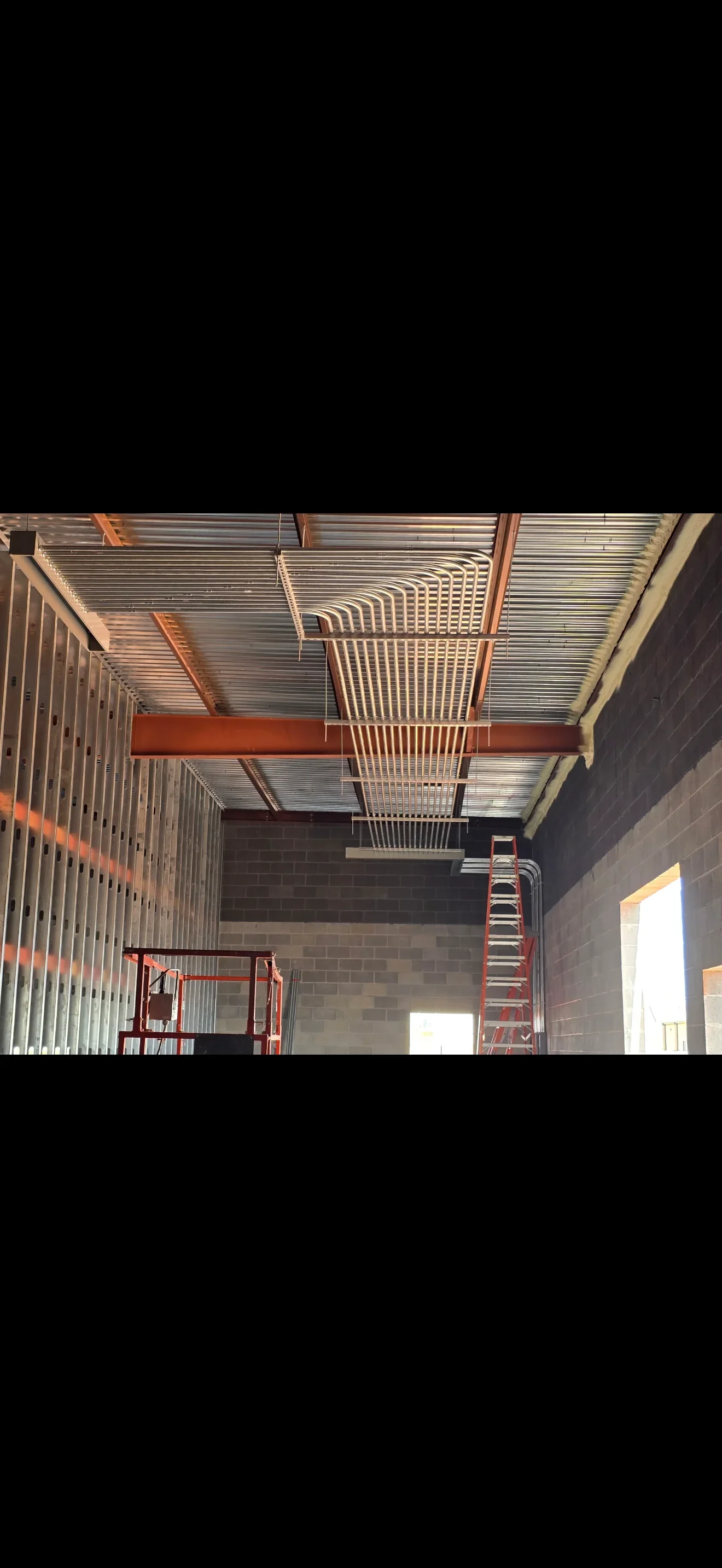 Industrial electrical conduit, cable trays, and raceways installed on steel beams and concrete block walls
